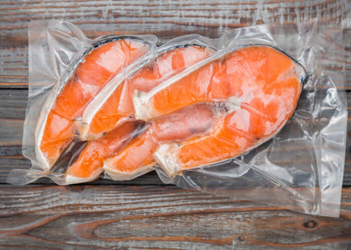Frozen salmon fillets in a vacuum package wood table